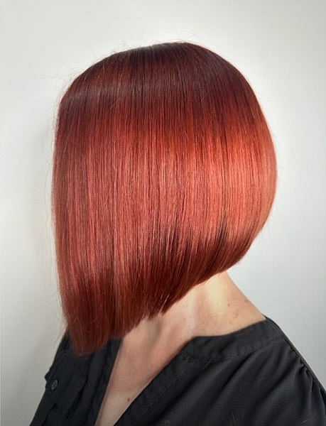 Sleek, angled bob hairstyle in vibrant red on a person with a dark shirt.